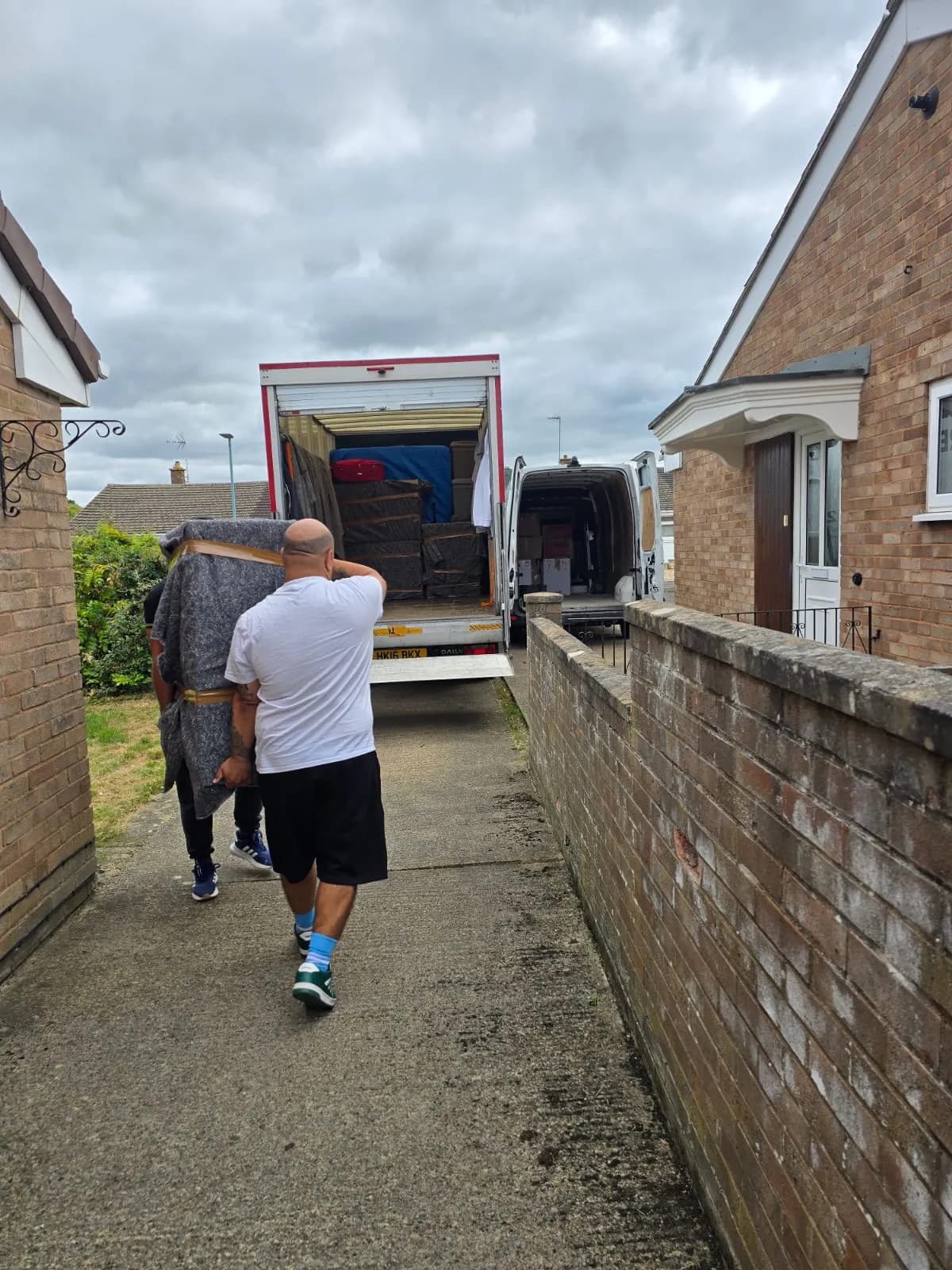 All Around Removals team carrying furniture down a garden path to the van