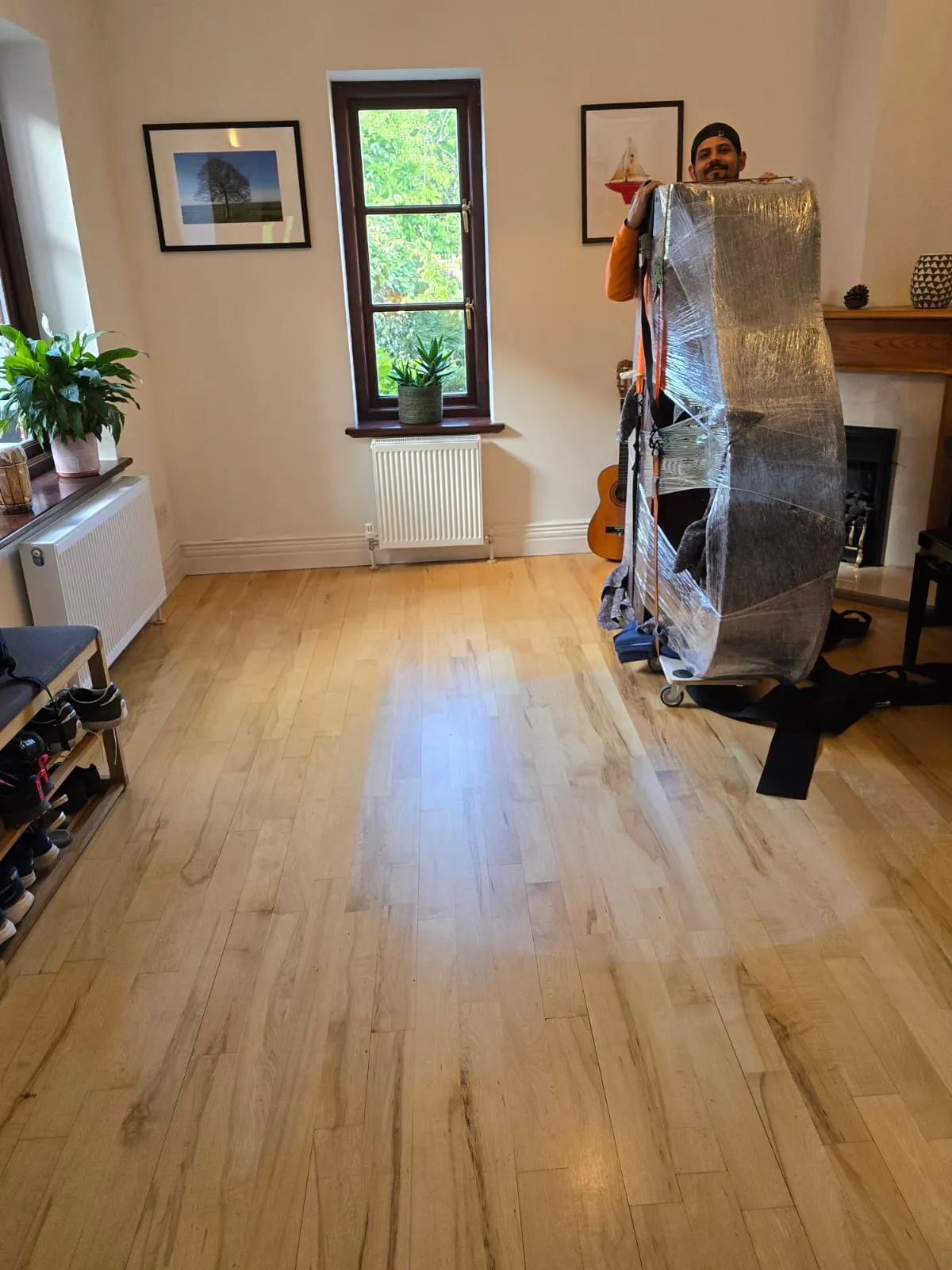 All Around Removals mover carrying a wrapped item through a living room