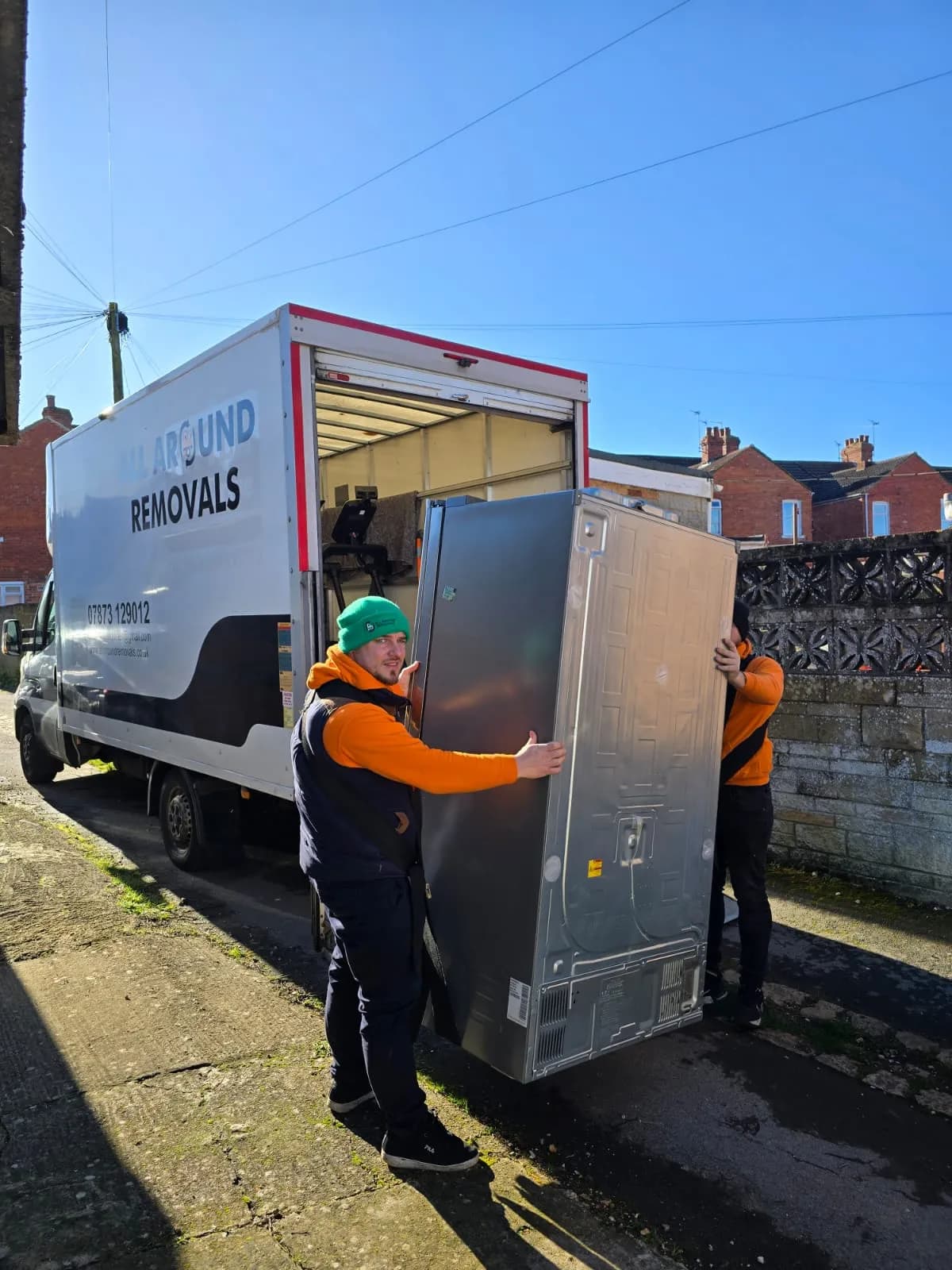 Two All Around Removals movers loading a fridge freezer into the van