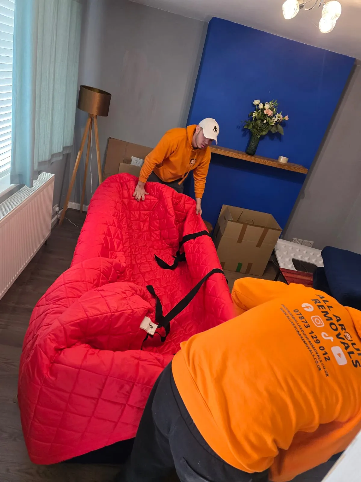 All Around Removals movers wrapping a sofa in protective removal blankets